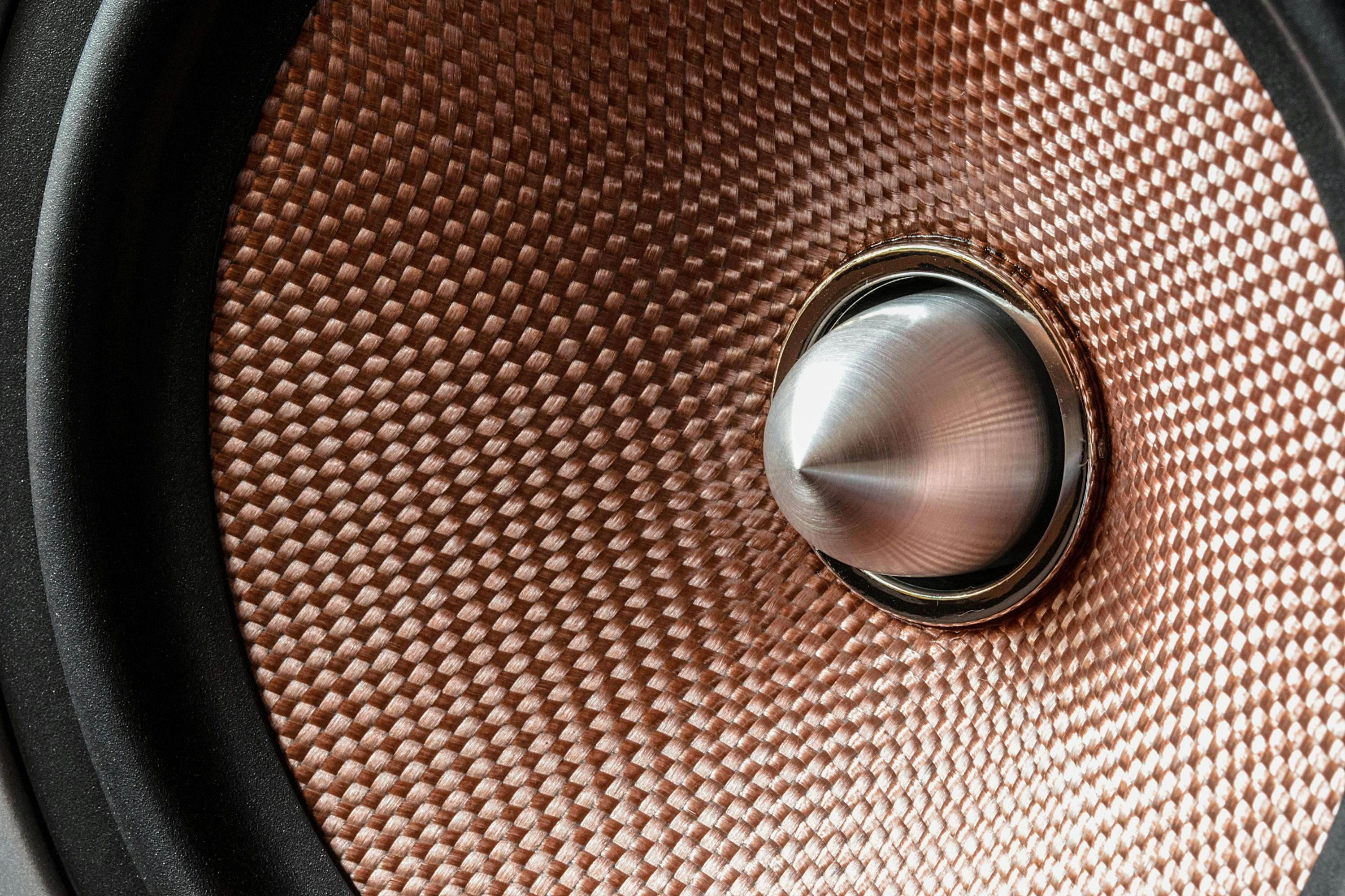 Detailed view of a metallic speaker cone with textured pattern and modern design.